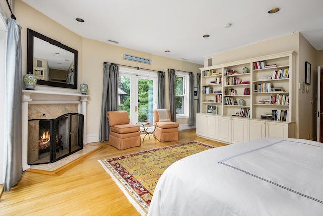 bedroom with light hardwood / wood-style flooring and a premium fireplace