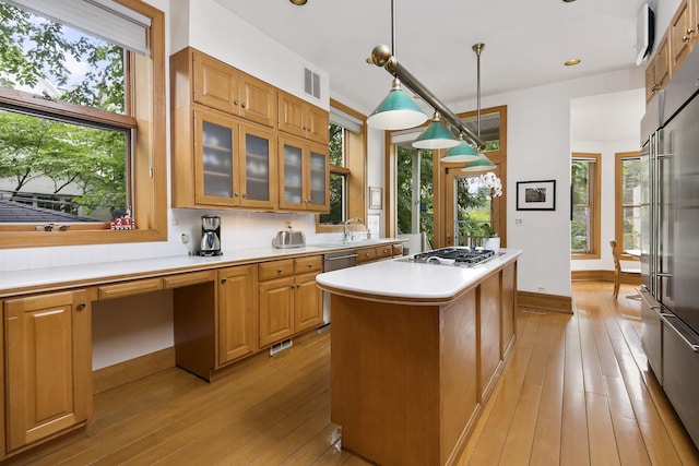 kitchen with decorative light fixtures, a center island, light hardwood / wood-style floors, and stainless steel appliances