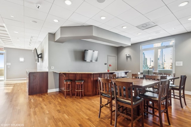 dining room featuring a drop ceiling and light hardwood / wood-style floors