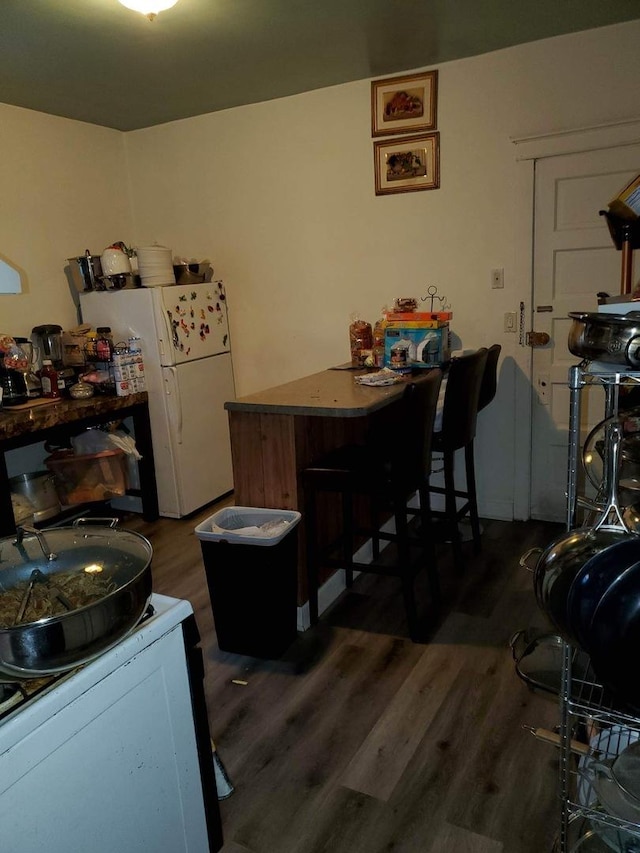 kitchen featuring kitchen peninsula, white fridge, and dark hardwood / wood-style floors