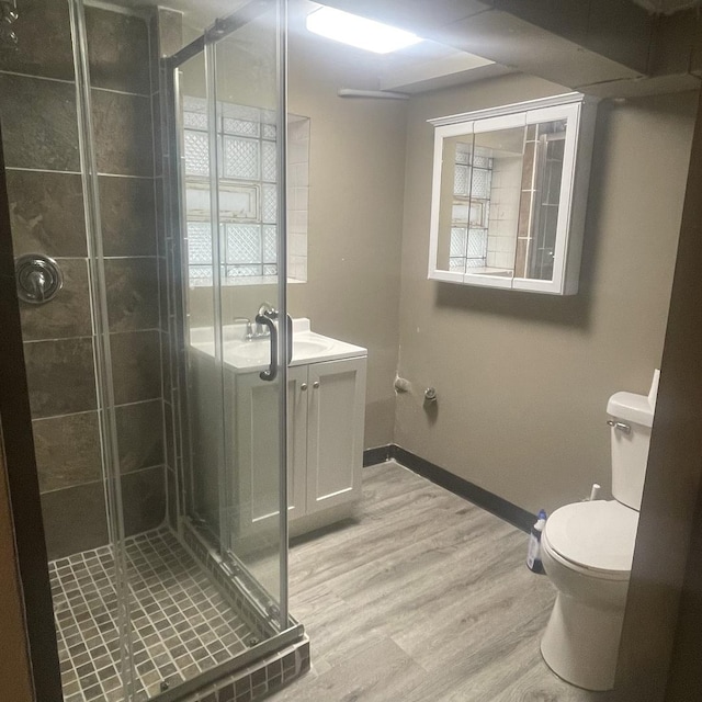 bathroom with hardwood / wood-style floors, vanity, toilet, and a shower with door