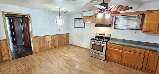 kitchen featuring pendant lighting, gas stove, light hardwood / wood-style floors, and wooden walls