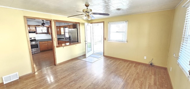 kitchen featuring ornamental molding, stainless steel appliances, ventilation hood, sink, and light hardwood / wood-style floors