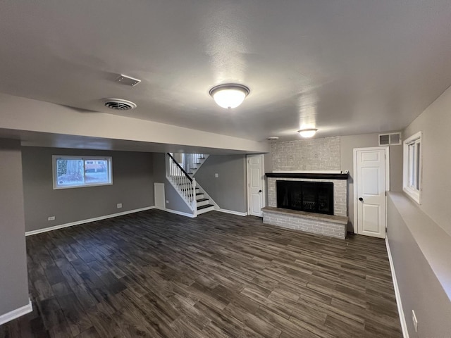 basement featuring dark hardwood / wood-style flooring and a brick fireplace