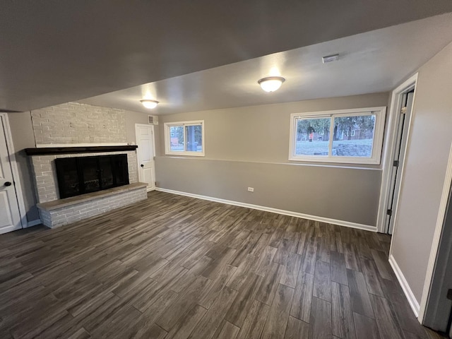 unfurnished living room featuring dark hardwood / wood-style flooring and a brick fireplace