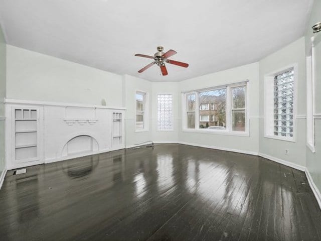 unfurnished living room featuring ceiling fan and dark hardwood / wood-style floors