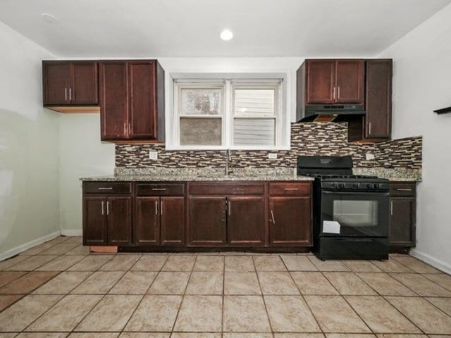 kitchen with sink, light stone counters, and black range with gas cooktop