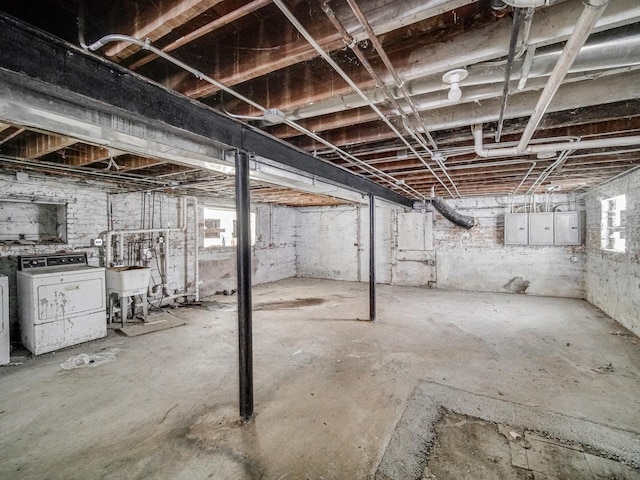 basement featuring a healthy amount of sunlight, washing machine and dryer, and electric panel