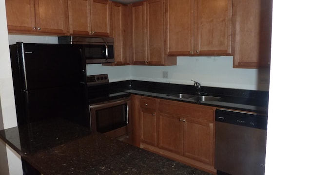 kitchen with dark stone countertops, sink, and appliances with stainless steel finishes