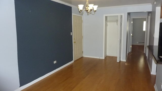 interior space with dark wood-type flooring, an inviting chandelier, baseboard heating, and ornamental molding