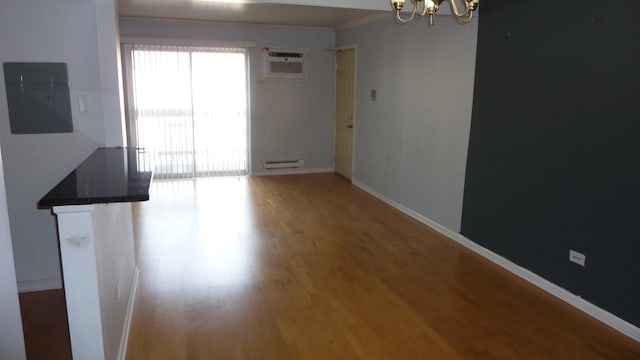 interior space with electric panel, a baseboard heating unit, hardwood / wood-style flooring, a notable chandelier, and a wall unit AC