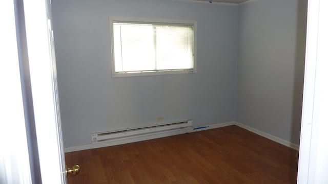 unfurnished room with dark wood-type flooring and a baseboard heating unit