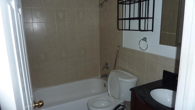 full bathroom with vanity, toilet, tile walls, and tiled shower / bath