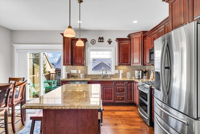 kitchen featuring stainless steel appliances, a center island, sink, and plenty of natural light