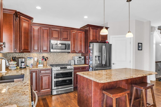 kitchen featuring stainless steel appliances, tasteful backsplash, a kitchen island, dark hardwood / wood-style flooring, and sink