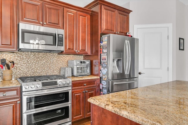 kitchen with light stone countertops, appliances with stainless steel finishes, and backsplash