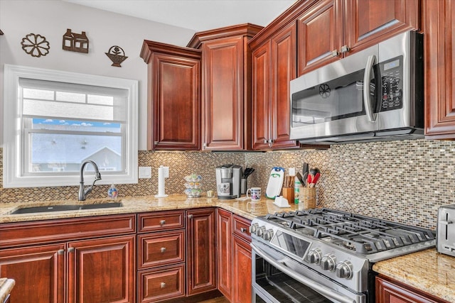 kitchen featuring stainless steel appliances, sink, backsplash, and light stone counters