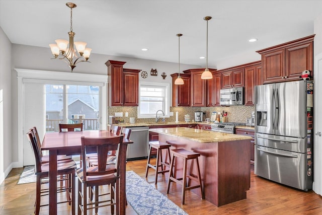 kitchen with stainless steel appliances, a chandelier, pendant lighting, and a center island