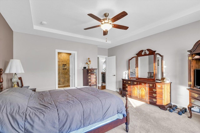 bedroom featuring ceiling fan, a raised ceiling, connected bathroom, and light carpet