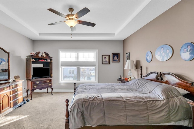 bedroom with ceiling fan, a tray ceiling, and carpet flooring