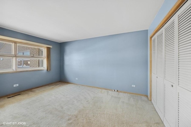 unfurnished bedroom with light colored carpet and a closet