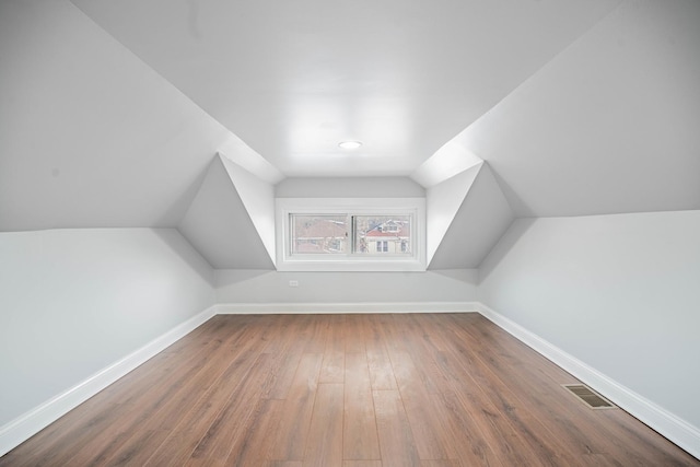 additional living space featuring wood-type flooring and vaulted ceiling