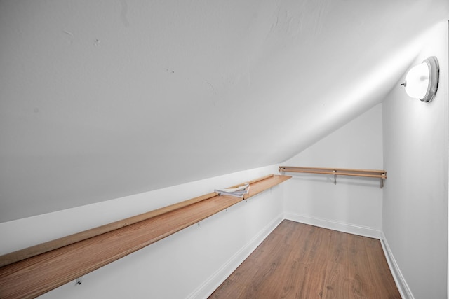 walk in closet with hardwood / wood-style floors and vaulted ceiling