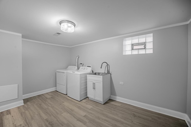 laundry room with washing machine and clothes dryer, light hardwood / wood-style flooring, ornamental molding, and sink