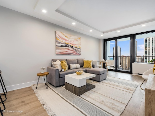 living room featuring light wood-type flooring and a tray ceiling