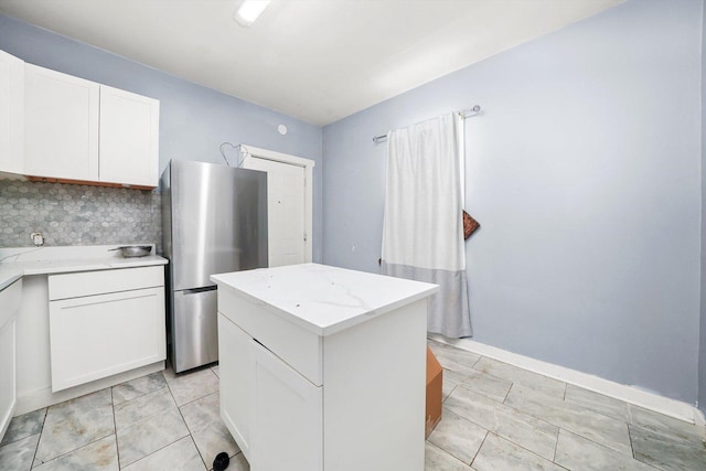 kitchen with stainless steel refrigerator, white cabinets, a kitchen island, and light stone counters