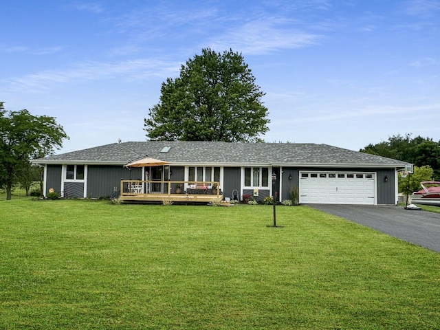 ranch-style home featuring a garage, a deck, and a front yard