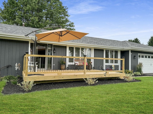 rear view of property with a garage, a yard, and a wooden deck