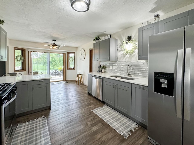 kitchen with backsplash, sink, ceiling fan, gray cabinets, and stainless steel appliances