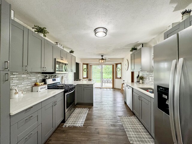 kitchen featuring gray cabinetry, decorative backsplash, kitchen peninsula, and stainless steel appliances