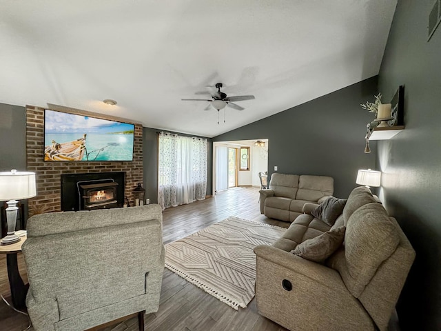 living room featuring hardwood / wood-style flooring, ceiling fan, a wood stove, and vaulted ceiling