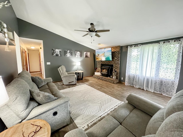 living room with hardwood / wood-style floors, vaulted ceiling, a wood stove, and ceiling fan