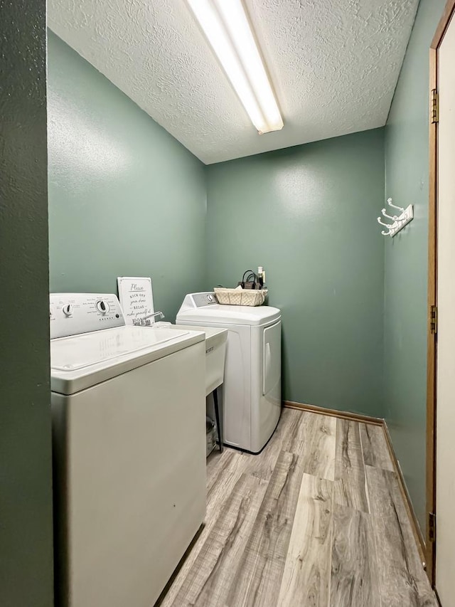 laundry room featuring light hardwood / wood-style floors, separate washer and dryer, and a textured ceiling