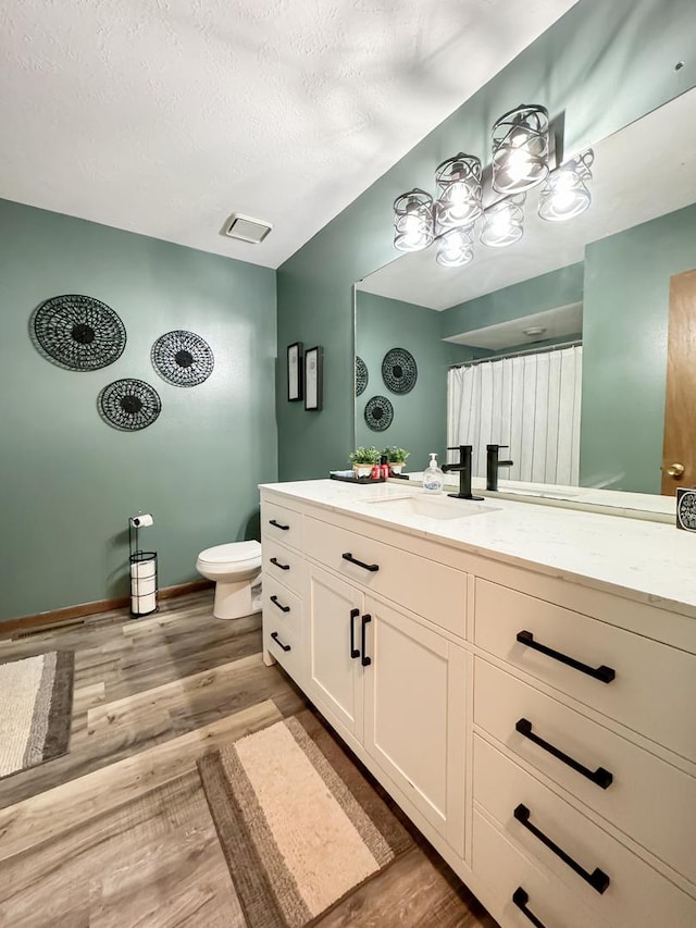 bathroom with toilet, vanity, a textured ceiling, and hardwood / wood-style flooring