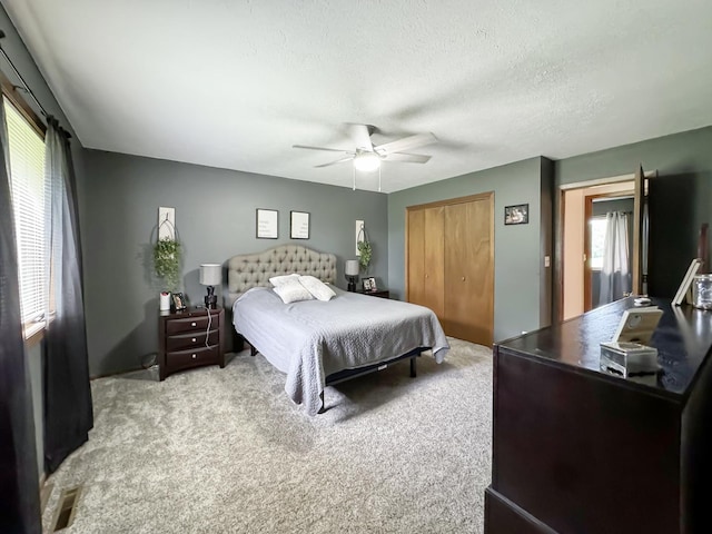 bedroom with ceiling fan, light colored carpet, a textured ceiling, and a closet