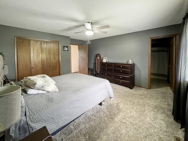 bedroom featuring ceiling fan, a closet, light carpet, and a textured ceiling