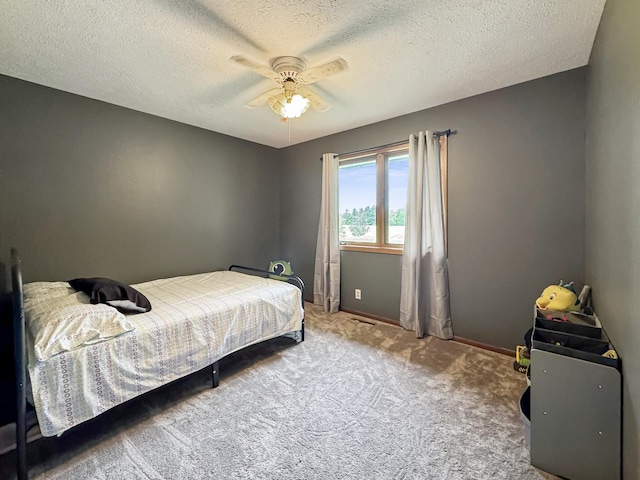 carpeted bedroom featuring ceiling fan and a textured ceiling