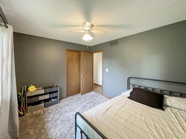 carpeted bedroom featuring ceiling fan and a textured ceiling