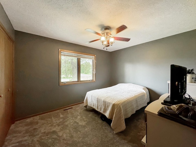 carpeted bedroom featuring ceiling fan and a textured ceiling