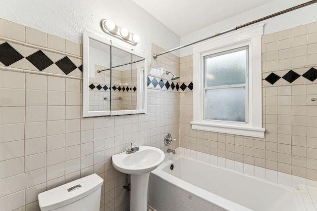 full bathroom featuring sink, toilet, tiled shower / bath, and tile walls