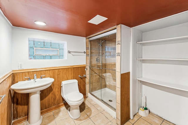 bathroom featuring walk in shower, wooden walls, sink, tile patterned flooring, and toilet