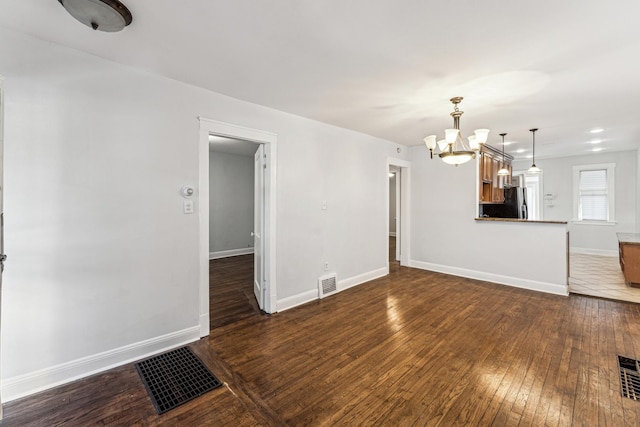 unfurnished living room with dark wood-type flooring and a notable chandelier