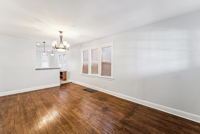 empty room with a chandelier and hardwood / wood-style flooring