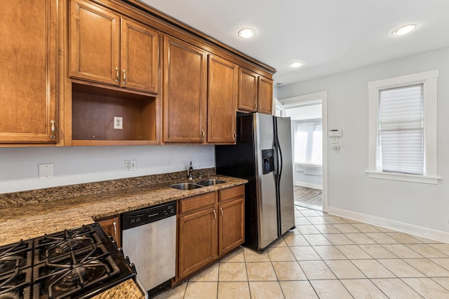 kitchen with sink, light tile patterned floors, stainless steel appliances, and dark stone counters