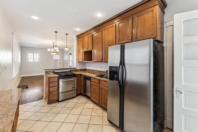 kitchen featuring sink, stainless steel appliances, a chandelier, decorative light fixtures, and light tile patterned floors