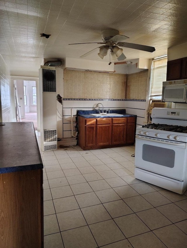 kitchen with white gas stove, ceiling fan, light tile patterned floors, and sink